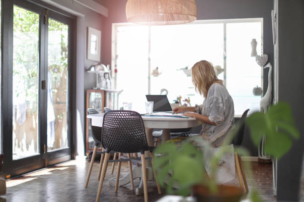 istock a Mature woman sketching on her dining table at home. 1129148307