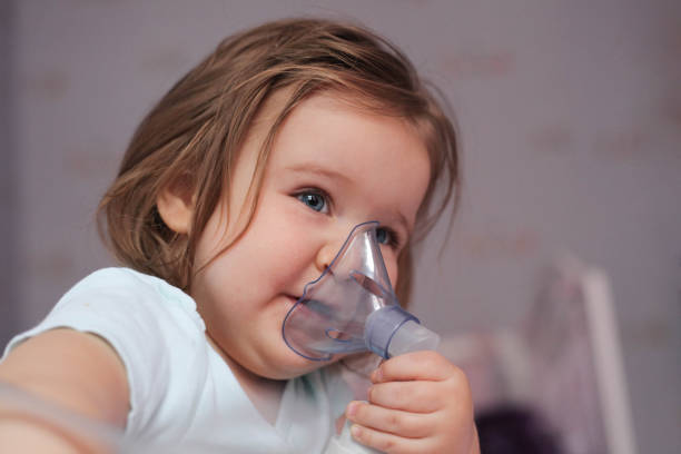 niña sonriente con inhaladores de asma. - tubing child oxygen mask medical oxygen equipment fotografías e imágenes de stock