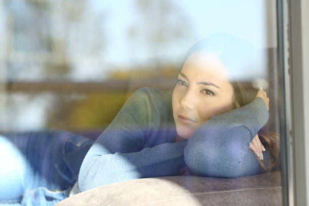 istock Serious woman thinking looking through a window 1129150040