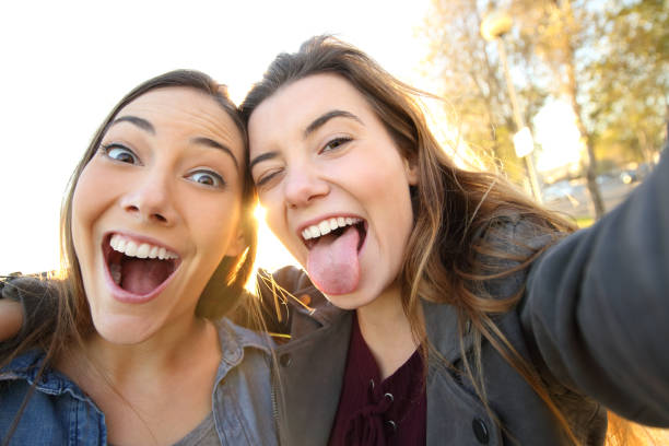 Funny women joking taking selfies in the street Funny women joking taking selfies in the street human tongue stock pictures, royalty-free photos & images