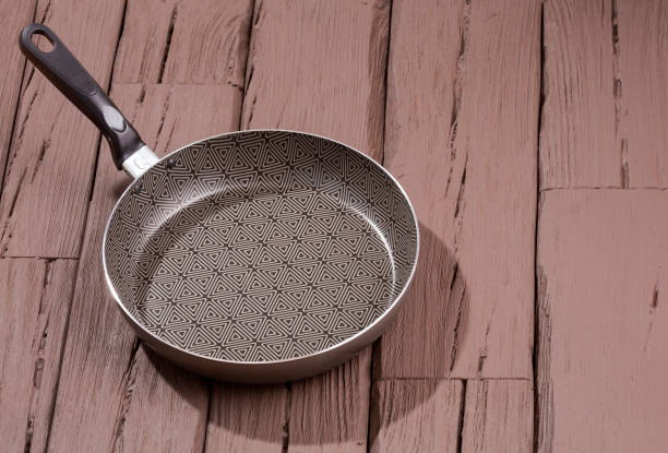 istock Black frying pan on wooden background 1129150680