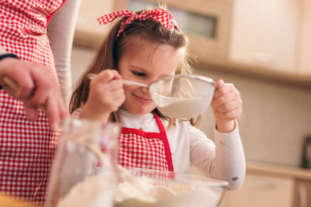 istock Mother and daughter sowing flour 1129151875