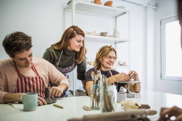 istock Mid adult woman molding clay while talking with instructor. 1129152178