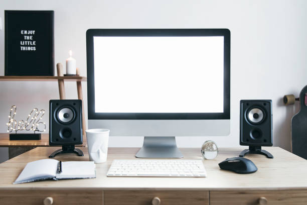 istock White scandinavian interior of home creative desk with mock up computer screen, photo frame, speakers and office accessories. Minimalistic space for work, hobby and listen music. 1129153074