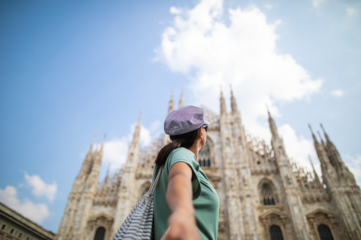 Rear view of woman looking at Duomo Di Milano and holding hand of unrecognizable person