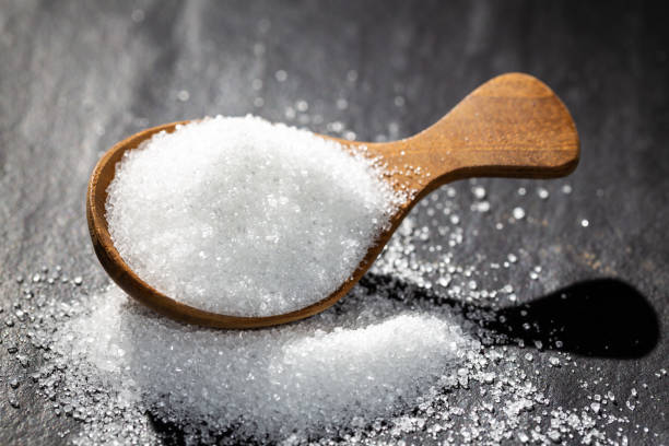 istock Sugar on a wooden spoon On a black background 1129154042