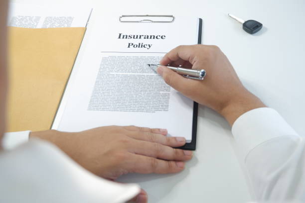 istock close-up man reading insurance policy, contract with car key on table 1129155192