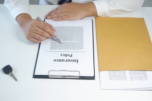 istock close-up man reading insurance policy, contract with car key on table 1129155199