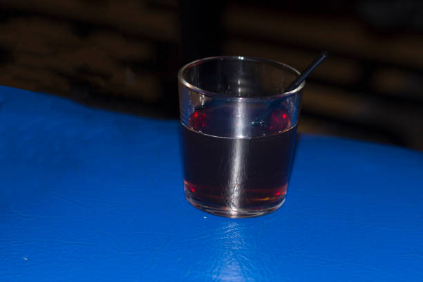a glass with a red mors and a black straw stands on a blue stand