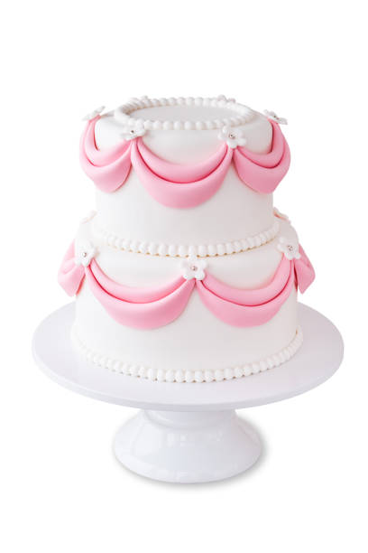 istock White wedding cake with pink elements made from pastry mastic isolated. 1129157908