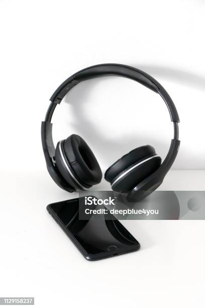 Bluetooth Headphones And Smartphone On White Stock Photo - Download Image Now - Cut Out, Headphones, Smart Phone