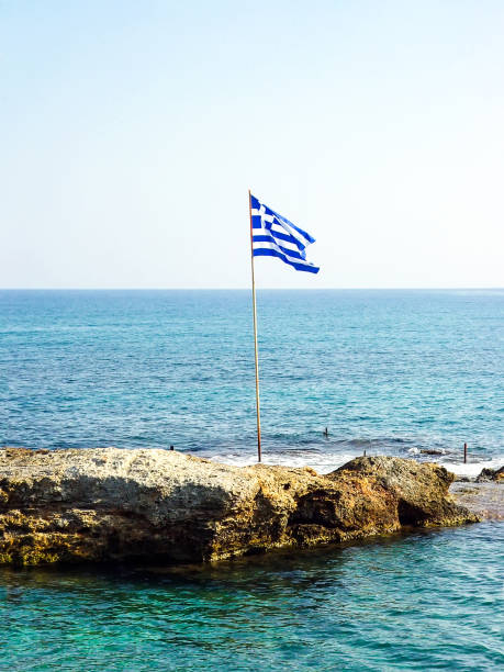 istock Greek flag on a small rocky island 1129160493
