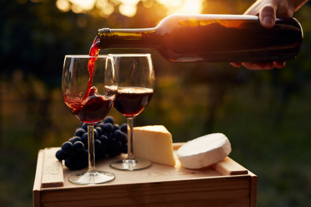 Pouring red wine into the glass in the vineyard Pouring red wine into the glass in the vineyard at sunset baguette photos stock pictures, royalty-free photos & images