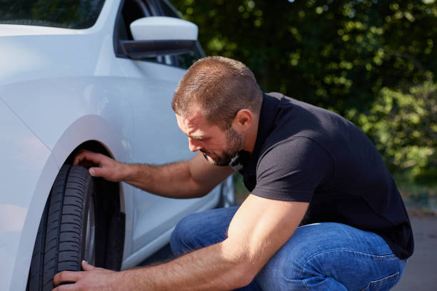 istock Man examining tires at his new car 1129162397
