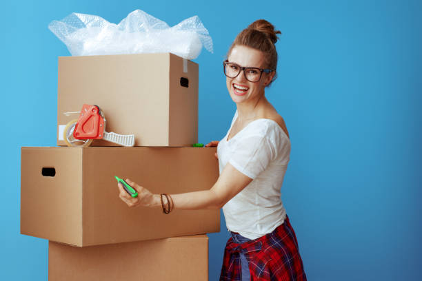istock smiling modern woman signs cardboard box on blue 1129167907