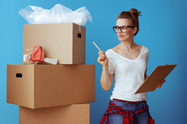 istock woman near cardboard box using moving checklist and count boxes 1129168544