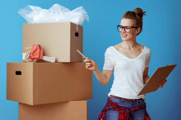 istock woman near cardboard box using moving checklist and count boxes 1129168595