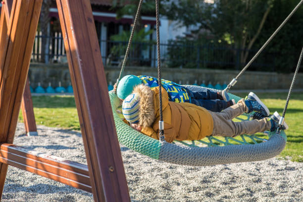istock Two boys in winter jacket lying on a big rope swing 1129169045
