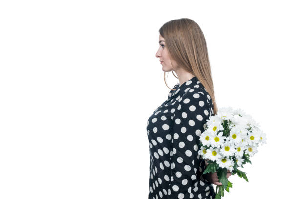 istock woman with flowers behind her back 1129170582