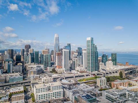 An aerial view of San Francisco skyline looking at Rincon Hill and many iconic buildings in the financial district. View includes a view of the 80 freeway, Bay Bridge and San Francisco Bay.