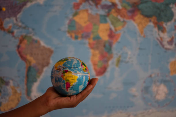 istock Hand holding globe against background of map 1129171154