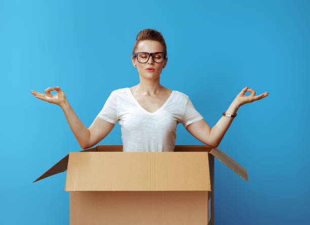 istock relaxed modern woman doing yoga in cardboard box on blue 1129171177