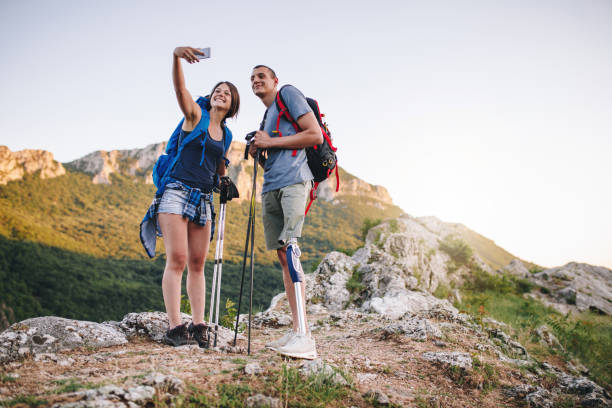 Young amputee hiker and his girlfriend taking a selfie in nature Young and determined amputee hiking the nature with his support, his girlfriend. disabled person hiking outdoors stock pictures, royalty-free photos & images