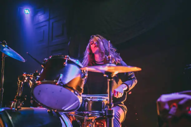 Woman drummer playing drums on stage in the club