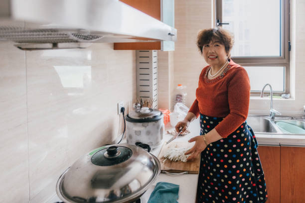 istock smiling chinese grandmother cooking in kitchen 1129173367
