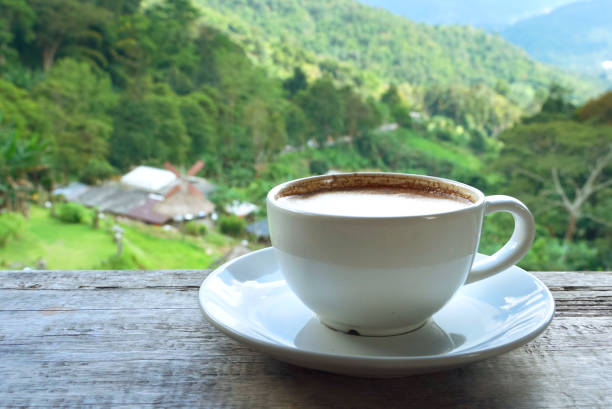 istock White coffee cup on wood table with background landspace mountain 1129175103