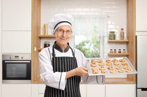 istock Elderly baker holding a tray with freshly baked cookies 1129176800