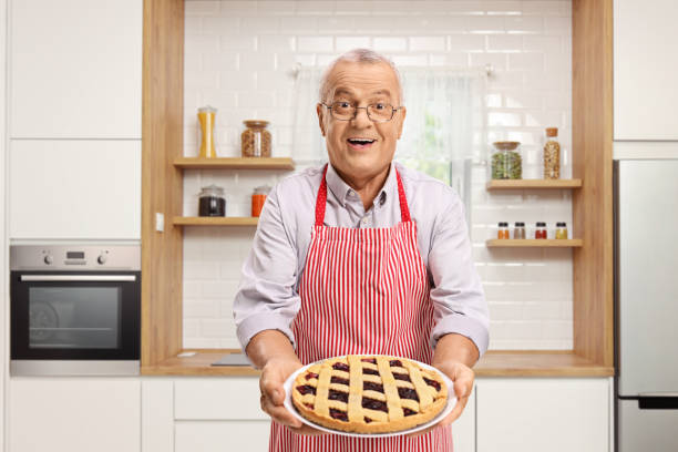 istock Mature man holding a freshly baked pie and standing in a kitchen 1129177034