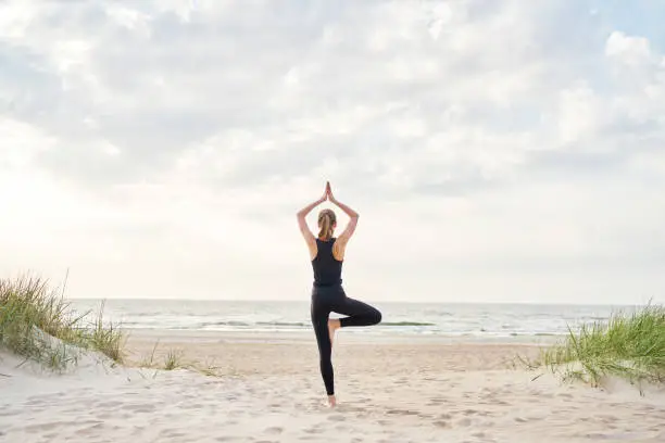Photo of Young woman doing yoga on the beach