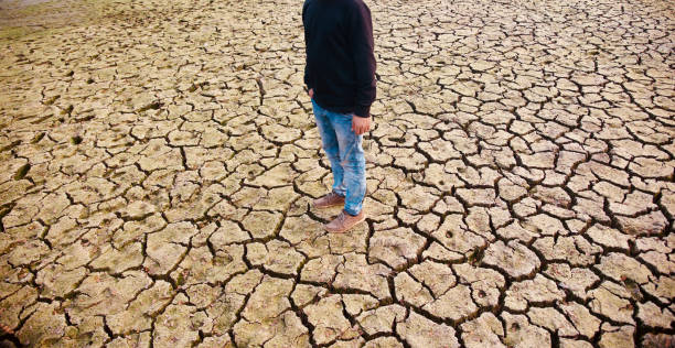 istock Young man wearing black dress standing on a dried soil surface 1129182224