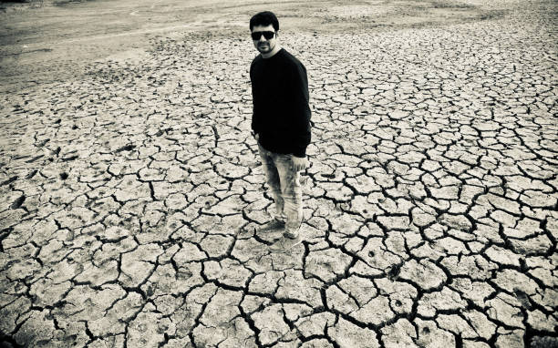 istock Young man wearing black dress standing on a dried soil surface 1129182246