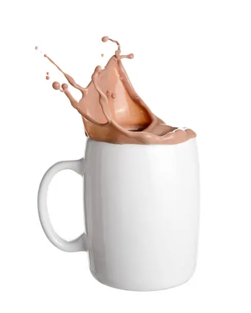 Chocolate milk splash out of white cup isolated on white background.