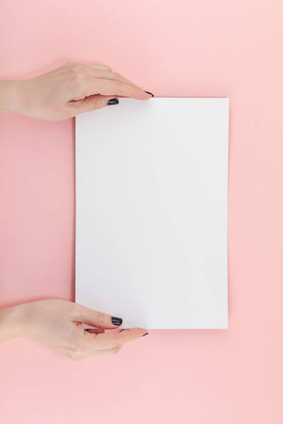 istock Woman hands with blank A4 paper sheet mockup 1129183798