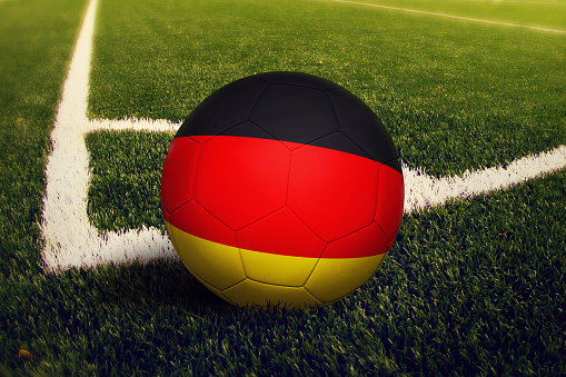 Germany ball on corner kick position, soccer field background. National football theme on green grass.
