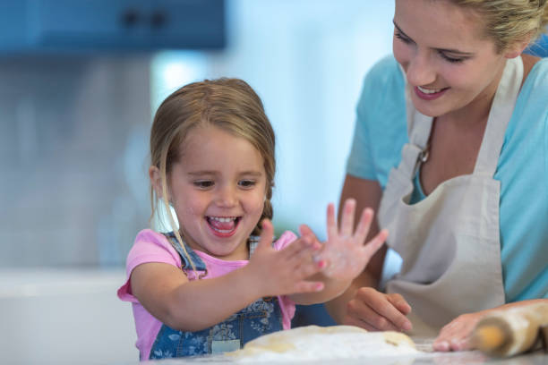 istock Mother and daughter rolling dough together 1129184054