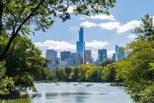 Unrecognizable people rowing in a lake during summer at Central Park, midtown Manhattan, New York City, USA.