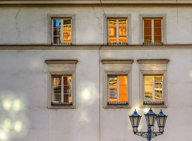 Street light and six old windows on the wall with reflections of the Old Town in Krakow at sunrise