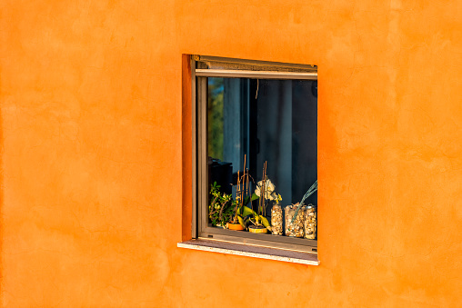 Chiusi sunset evening in Umbria, Tuscany Italy with closeup of window on traditional orange house or apartment flat in city with vibrant color