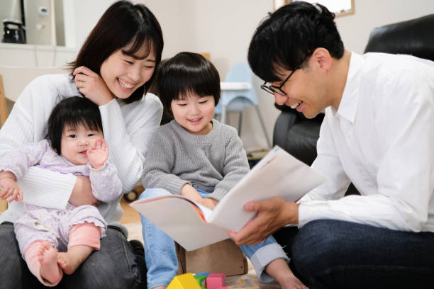 father reading book to child and baby - asian ethnicity child four people couple imagens e fotografias de stock