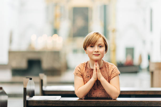istock Little boy praying in church 1129189398