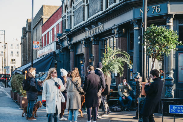 menschen zu fuß auf einer straße mit pflanzen gekauft an der columbia road flower market, london, uk. - hackney stock-fotos und bilder