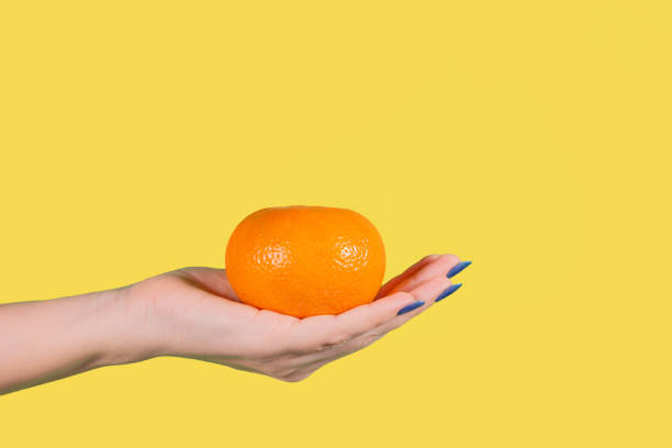istock female hand holding big orange ripe mandarin 1129195723