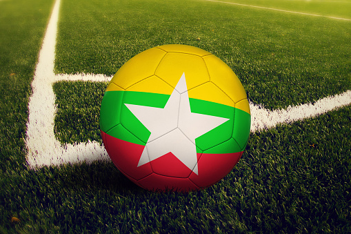 Myanmar ball on corner kick position, soccer field background. National football theme on green grass.