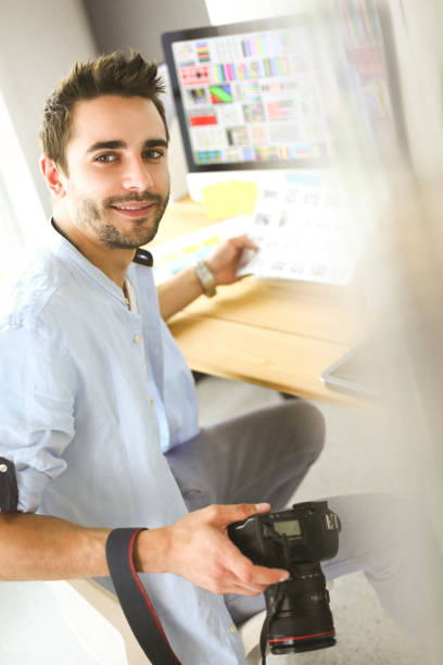Portrait of young designer sitting at graphic studio in front of laptop and computer while working online