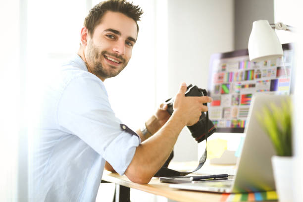 istock Portrait of young designer sitting at graphic studio in front of laptop and computer while working online 1129196997