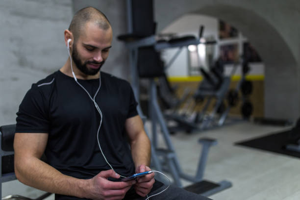 istock Smiling man in the gym using smart phone 1129197449